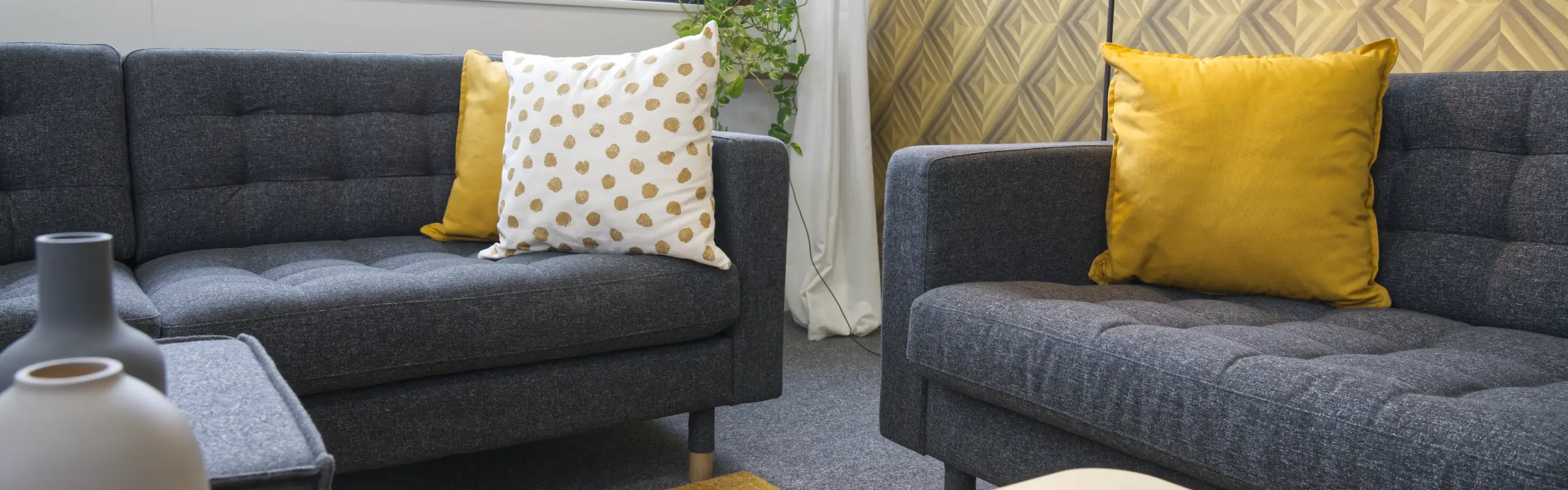 Moderne Sitzecke mit grauen Sofas und gelben Akzentkissen im Büro der Familienheim Karlsruhe eG.